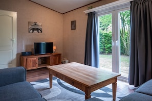 A living room with a television, a wooden table, and a sofa. - Country Estate de Berghorst (Stegeren)