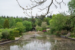 A serene pond surrounded by lush greenery and a wooden fence. - Country Estate de Berghorst (Stegeren)
