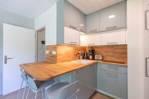 A compact kitchen with a wooden countertop, a sink, and modern cabinetry. - Le Nid des Cimes - Proche de la navette des pistes (Barèges)