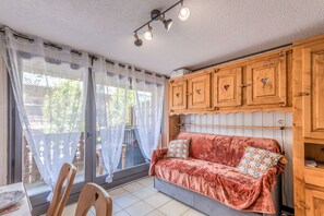 Ein gemütliches Zimmer mit einer gepolsterten Couch, Holzausbau und einer Essecke mit Stühlen und Tisch.