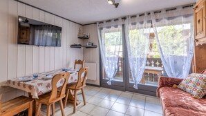 En matplats med ett bord dukat för två personer, trästolar, en soffa och ett fönster med gardiner.