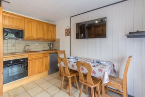 Eine Küche mit Holzausstattung, einer Mikrowelle, einem Backofen und einem Esstisch mit Stühlen.