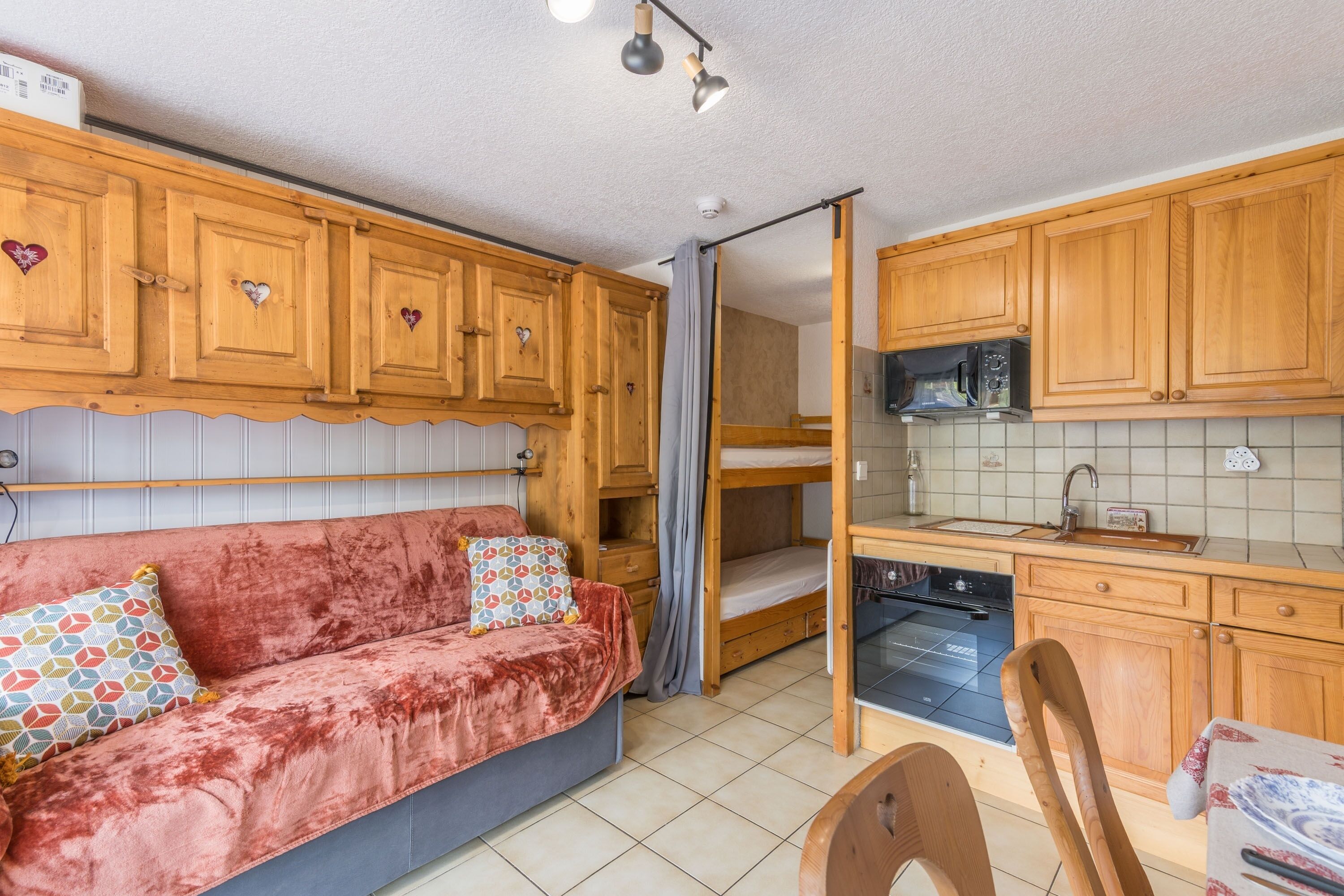 A compact kitchen with wooden cabinets, a microwave, and a stove.