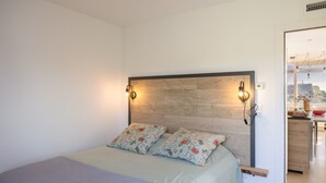 Una camera da letto con un letto, due luci a parete, una testiera in legno e vista su un angolo cottura.