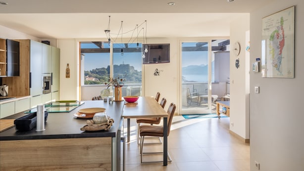 Una cucina moderna con zona pranzo, ampie finestre e vista mare.