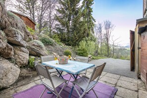 Eine Terrasse mit Tisch und Stühlen, eine Steinmauer und ein Holzhaus.