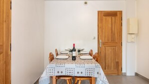 A dining area with a table set for four, a bottle of wine, and a wooden door. - Chez Sissi - Appt proche d'une remontée mécanique (Villarembert)