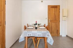 Ein Essbereich mit einem Tisch für vier Personen, einer Weinflasche und einer Holztür.