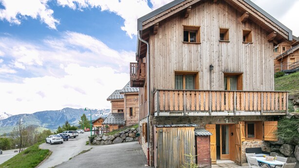 A wooden chalet with a balcony, a stone wall, and a view of mountains. - Chez Sissi - Appt proche d'une remontée mécanique (Villarembert)