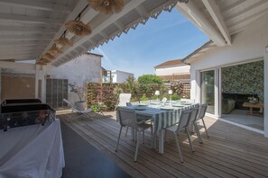 Eine Terrasse im Freien mit Esstisch, Grill und überdachter Sitzecke.