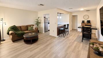A spacious living room with a sofa, coffee table, and a dining area with chairs and a table.