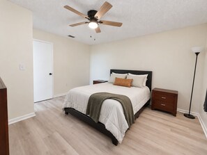 A bedroom with a bed, a nightstand, a floor lamp, and a ceiling fan. - The Sunshine Villa - Sebring (Sebring)