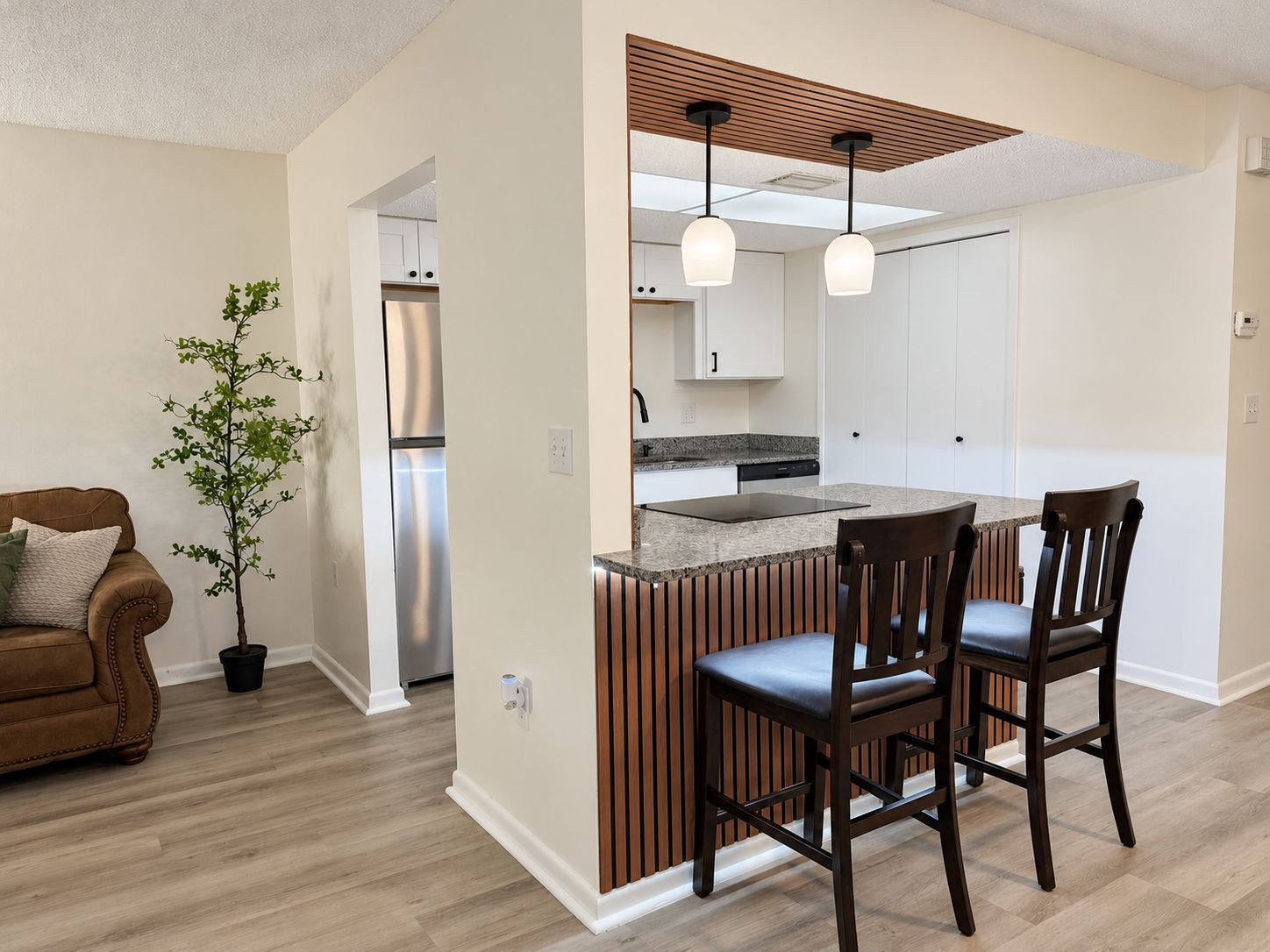 Una cocina moderna con una isla integrada, detalles en paneles de madera e iluminación colgante.