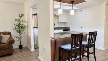 Una cocina moderna con una isla integrada, detalles en paneles de madera e iluminación colgante.