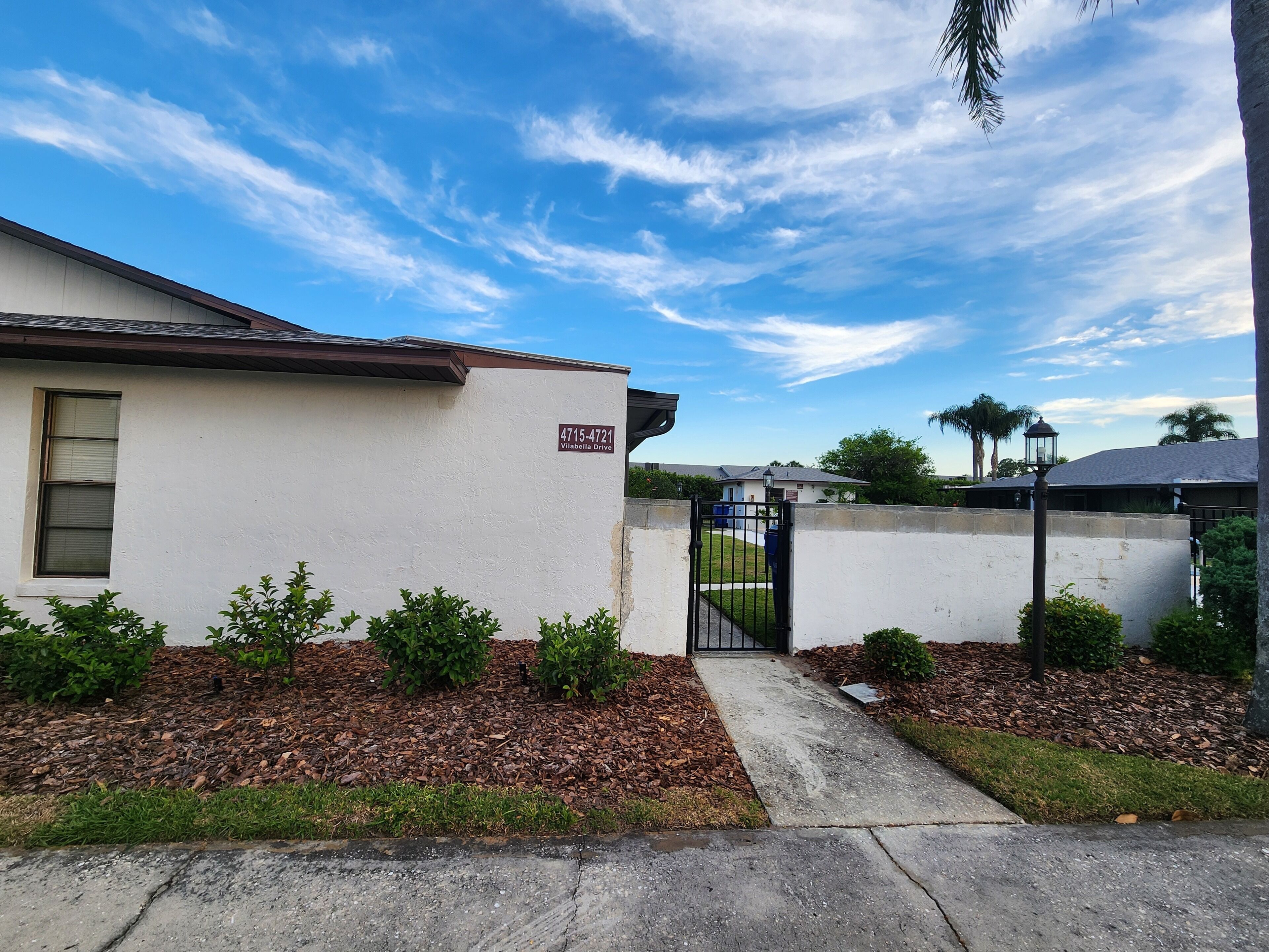 A residential building with a white exterior, a mailbox, and a gated entrance.