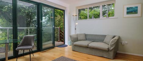 Una sala de estar moderna con una mesa de vidrio, un sofá gris y una mesita de centro de vidrio.