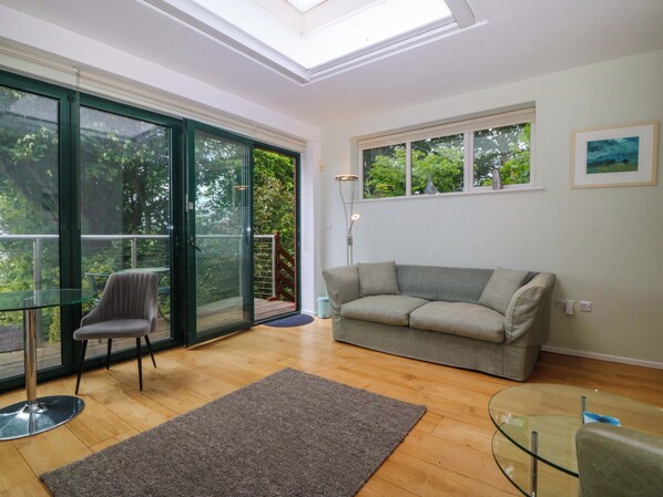 A modern living room with a glass table, a grey sofa, and a glass coffee table.