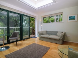 A modern living room with a glass table, a grey sofa, and a glass coffee table.