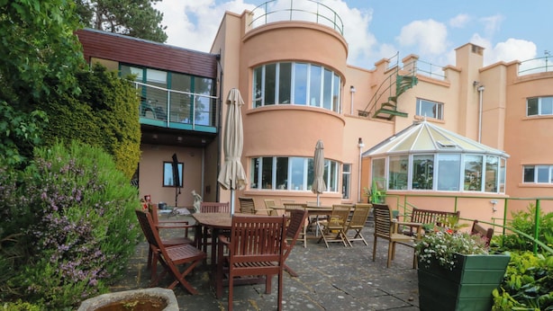 A patio area with outdoor furniture, a stone fountain, and a conservatory. - The Treehouse (Colwyn Bay)
