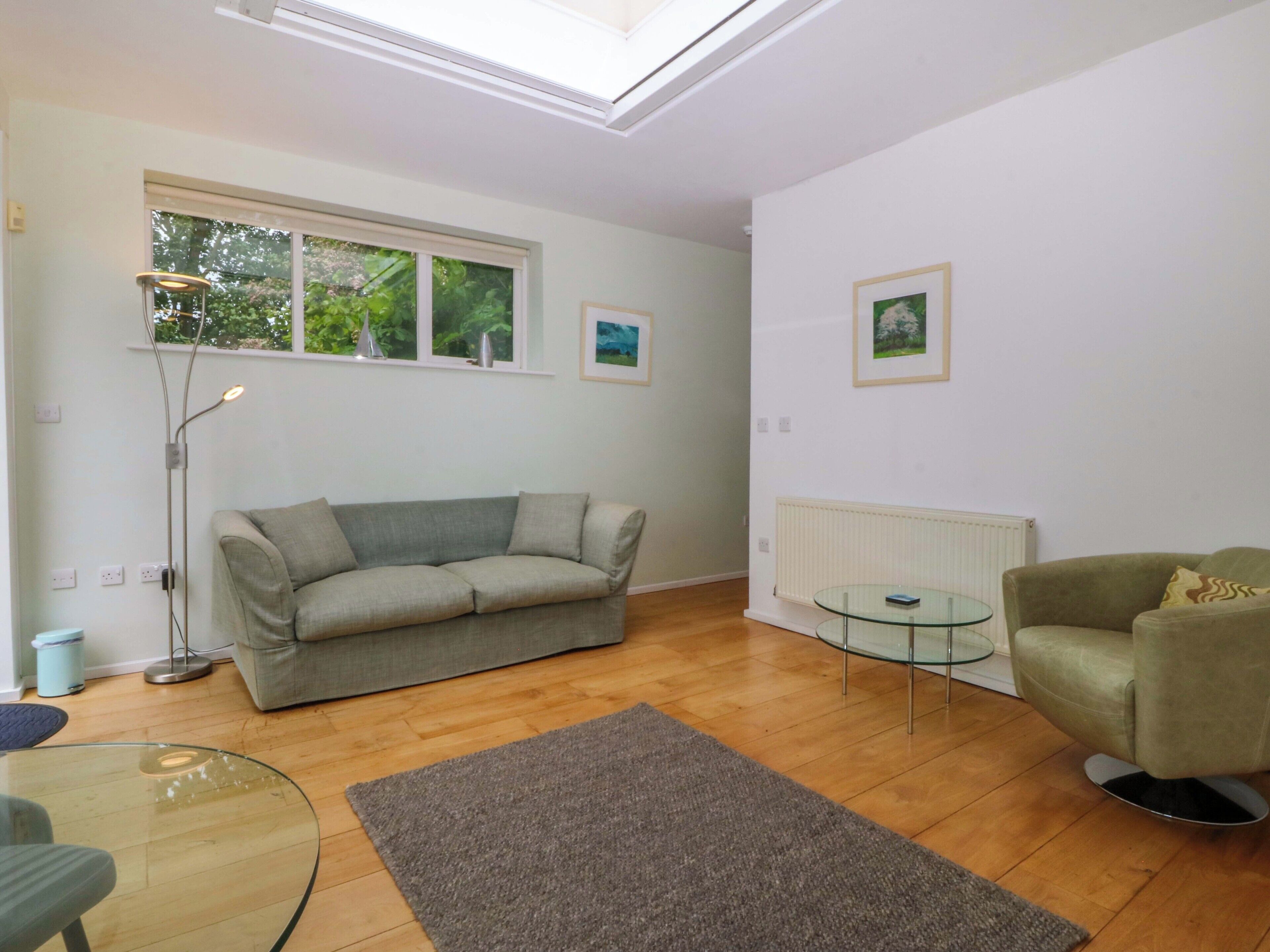 A living room with a sofa, a glass table, a floor lamp, and a radiator.