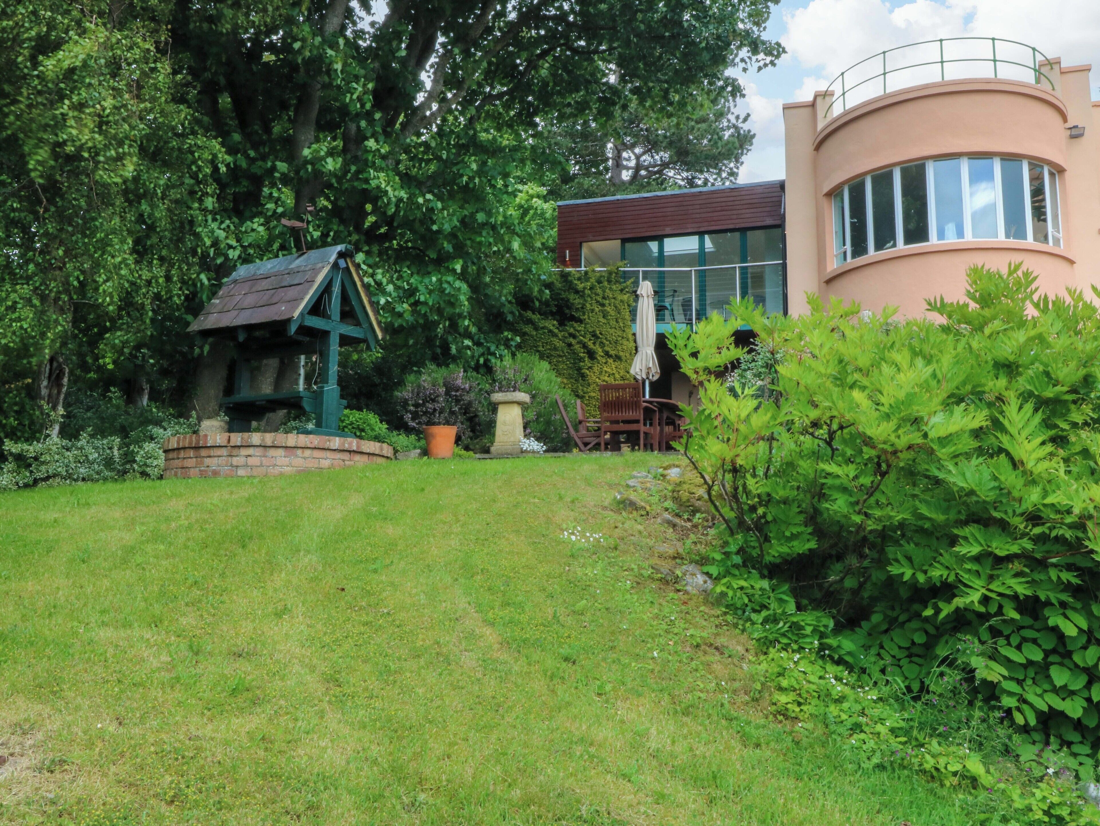 A house with a garden, a wooden structure, and a large tree.