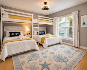 Ein Zimmer mit Etagenbetten, einem Nachttisch mit Lampe, einem Fenster mit Vorhängen und einem gemusterten Teppich.