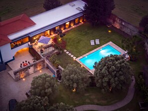 Vista aérea de una casa moderna con piscina, mobiliario exterior y un hogar para fogata.