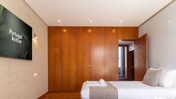 A hotel room with two beds, wooden wardrobe, and a television on the wall.