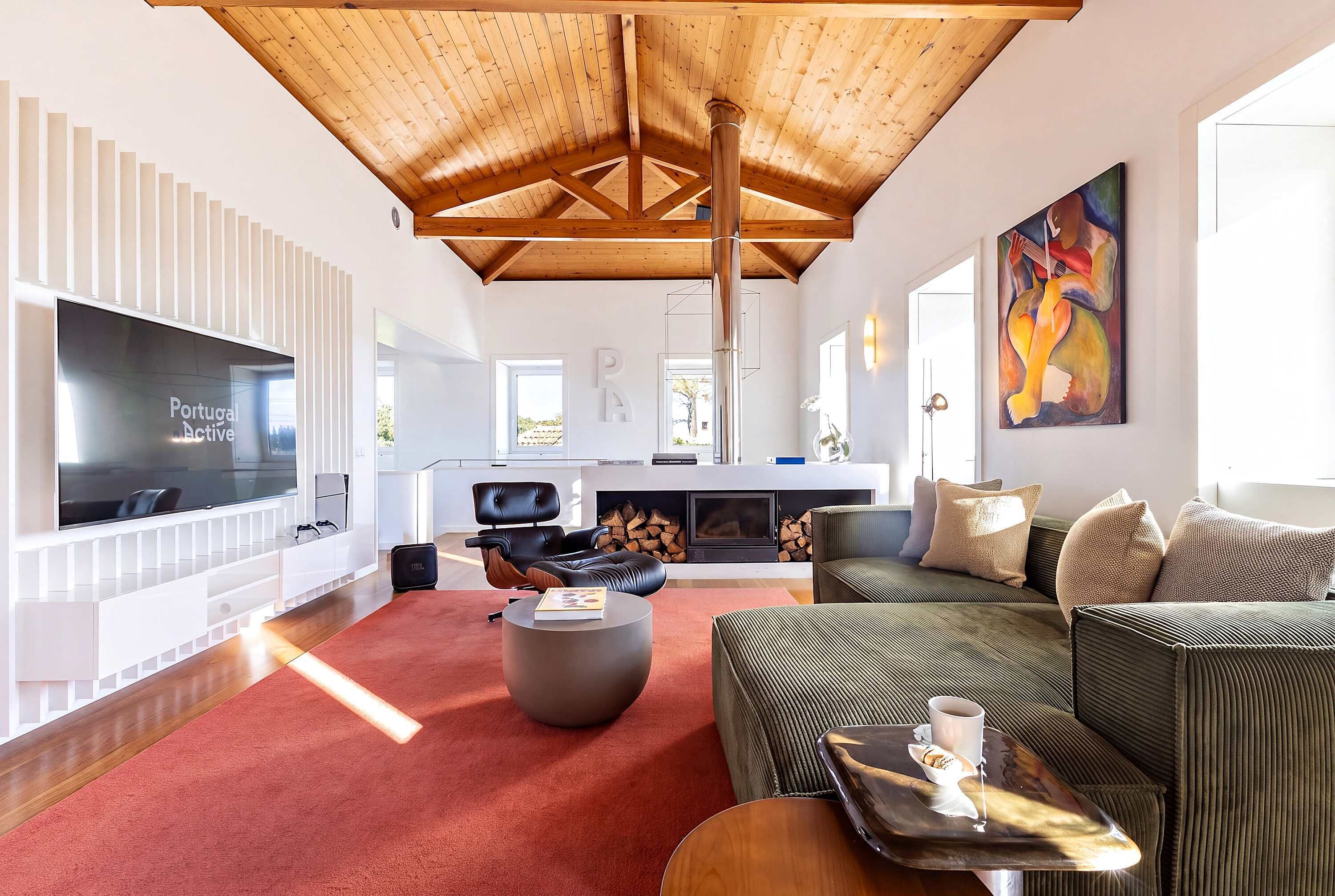 A spacious living room with a high ceiling, a fireplace, a large TV, and comfortable seating.