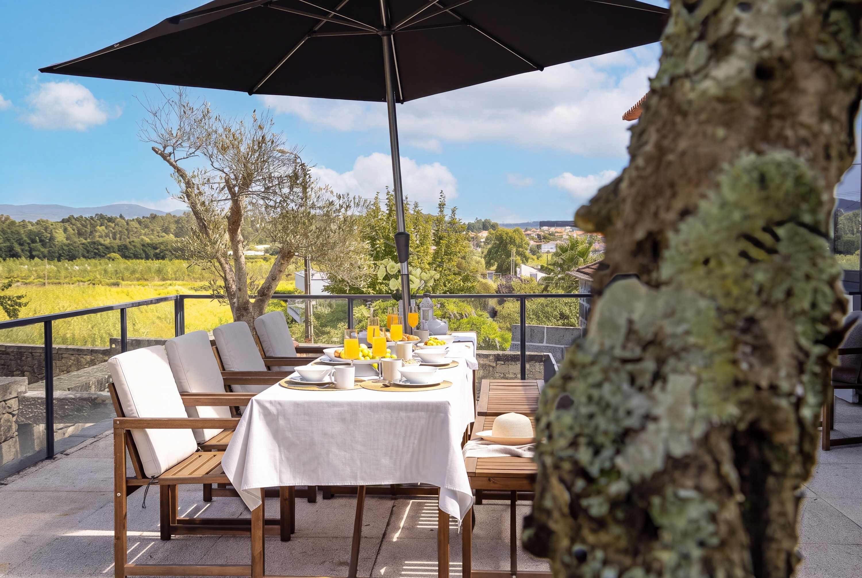 An outdoor dining area with a table set for breakfast, overlooking a scenic landscape.