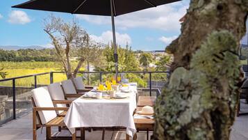 An outdoor dining area with a table set for breakfast, overlooking a scenic landscape.