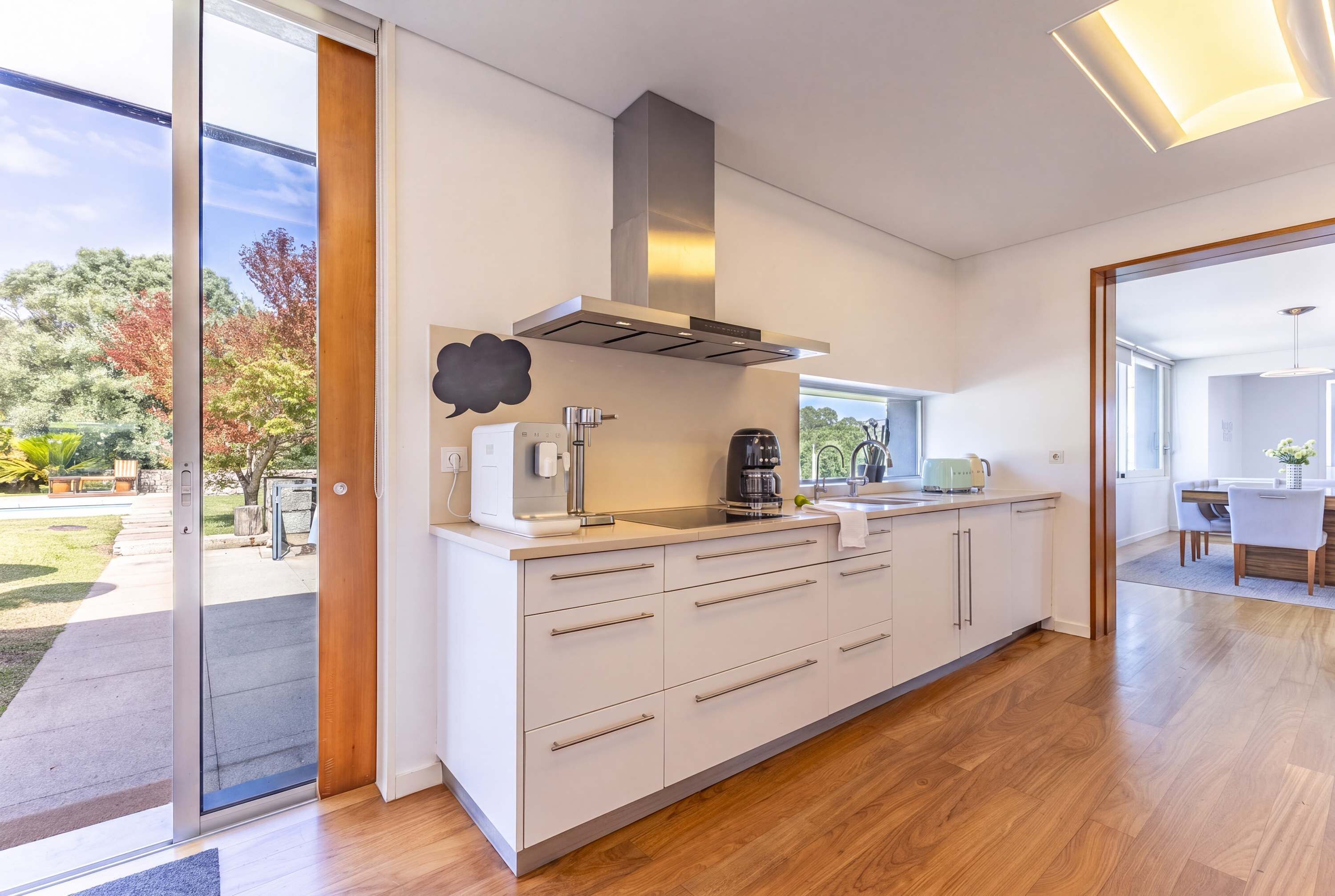 A modern kitchen with a large island, stainless steel appliances, and a view of the outdoors.