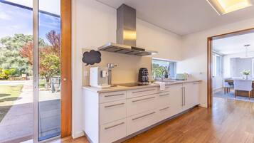 A modern kitchen with a large island, stainless steel appliances, and a view of the outdoors.