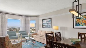 Een hotelkamer met balkon, een bank, een eettafel en stoelen.
