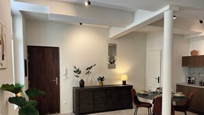 Una cocina moderna con zona de comedor, que cuenta con encimera de mármol, armarios oscuros y una isla central.