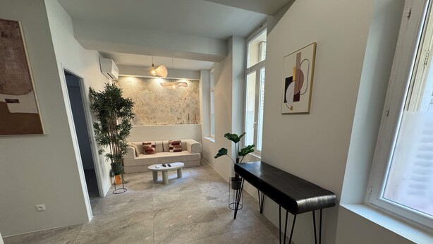 Un interior moderno con un sofá, una mesa de centro, un banco y una planta en maceta.