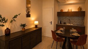Una cocina moderna con comedor, que incluye un armario de madera oscura, una mesa redonda con sillas y una lámpara fijada a la pared.