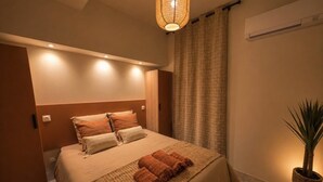 Un dormitorio con cama, lámpara de noche, planta en maceta y equipo de aire acondicionado.