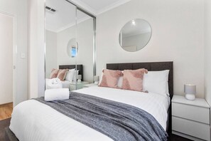 A hotel room with a bed, a bedside table with a lamp, a mirror, and a wardrobe. - Newly Built Retreat near Hillarys Boat Harbour (Craigie)