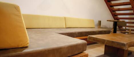 A modern interior with a sectional sofa, a wooden coffee table, and a staircase.