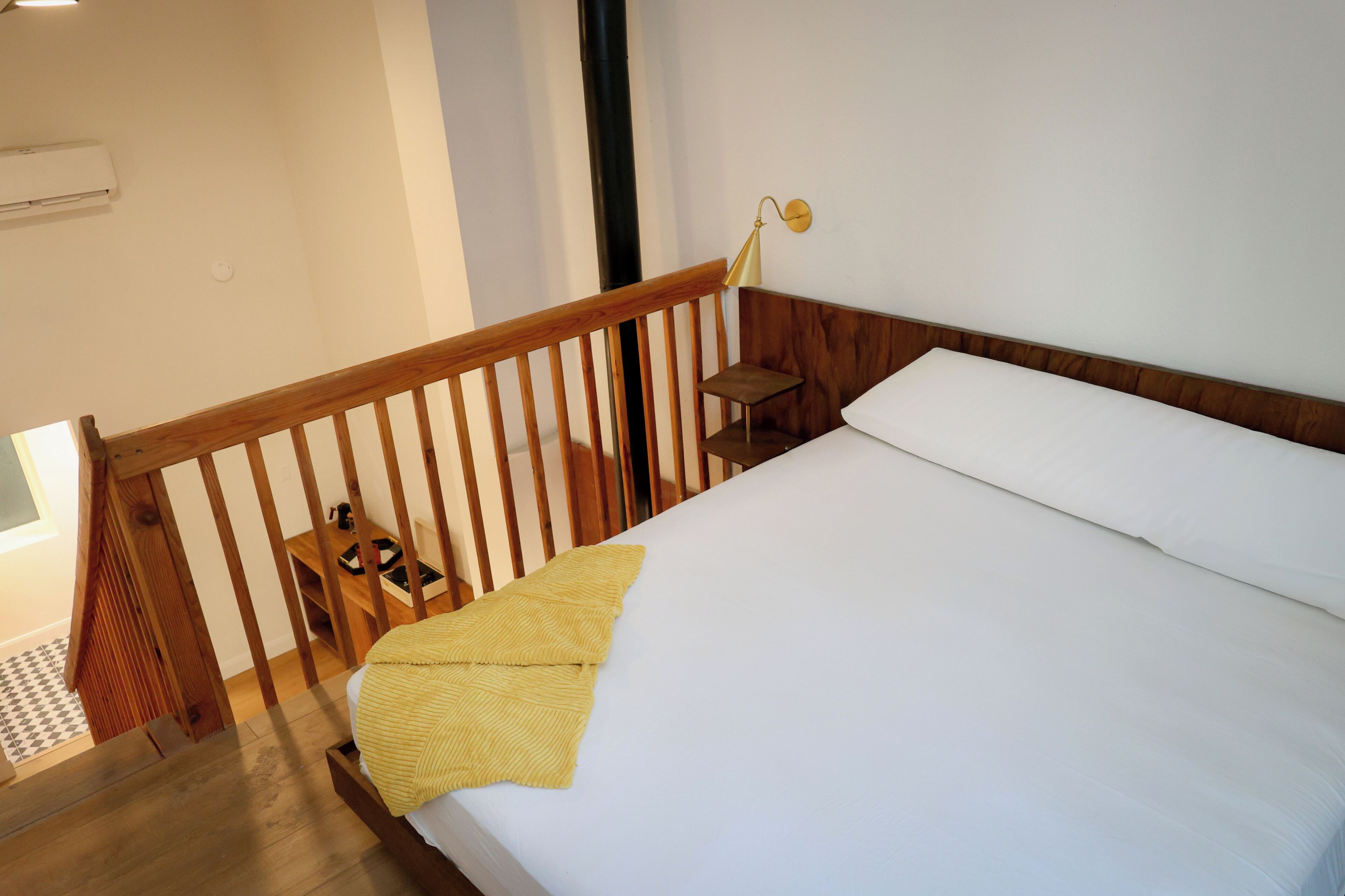 A bedroom with a wooden bed, a nightstand, a lamp, and a window.