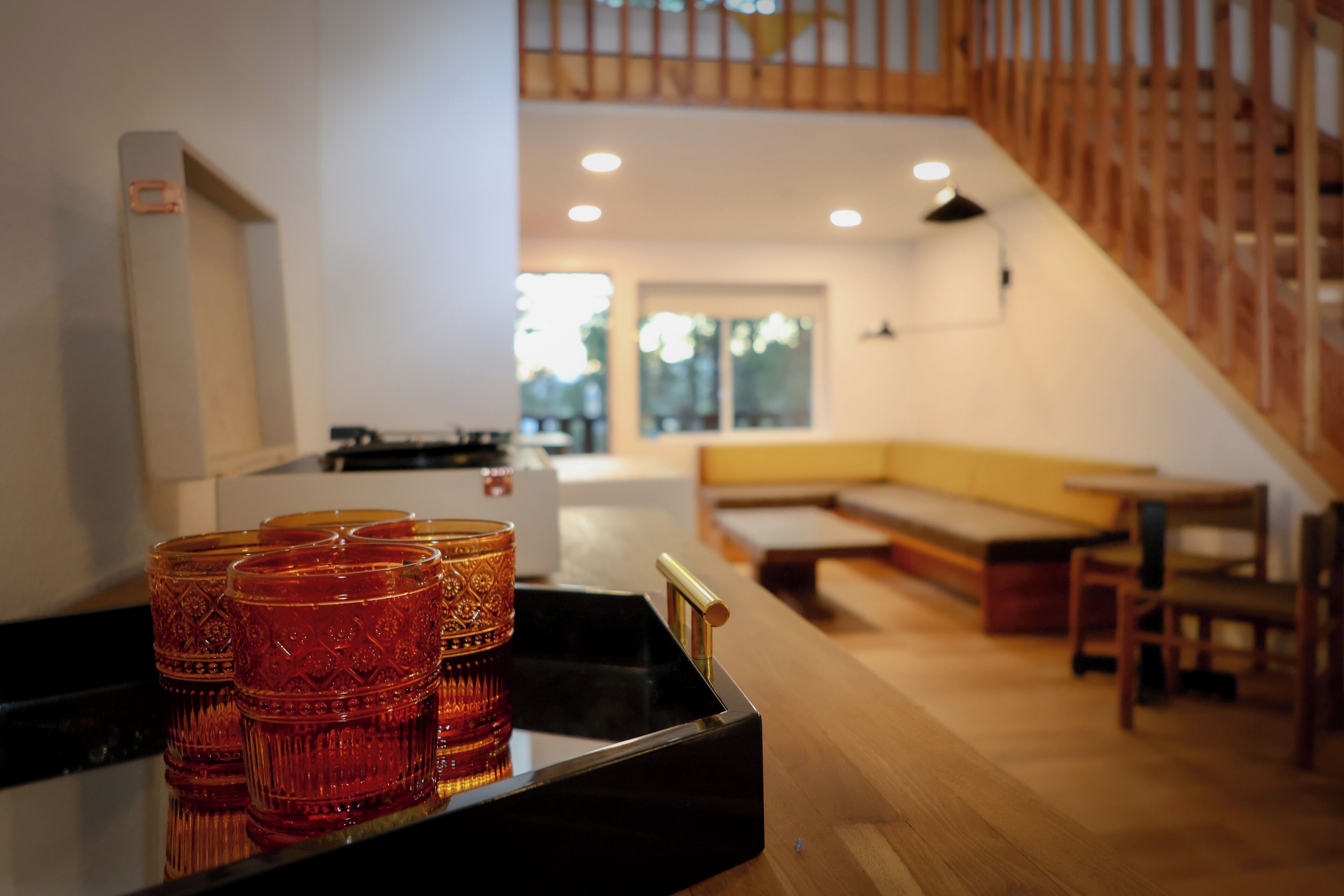 Een modern interieur met een houten trap, een keukenhoek en een zithoek met een bank en tafel.