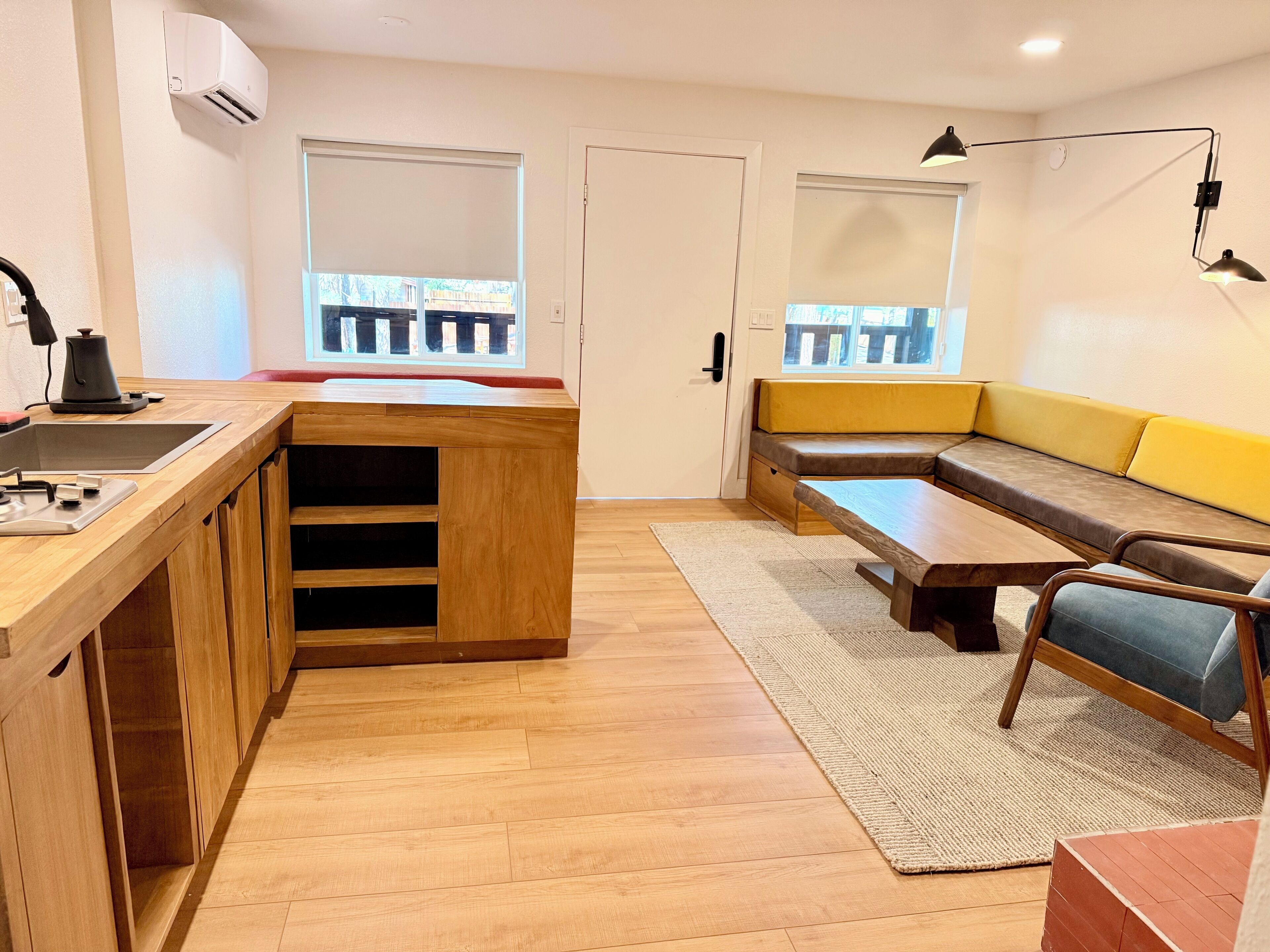 A compact living space with a kitchenette, a sofa, a dining table, and a window with a view.