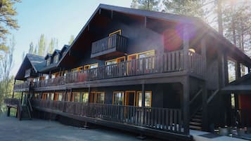 A multi-story wooden cabin with balconies, a staircase, and a covered porch.