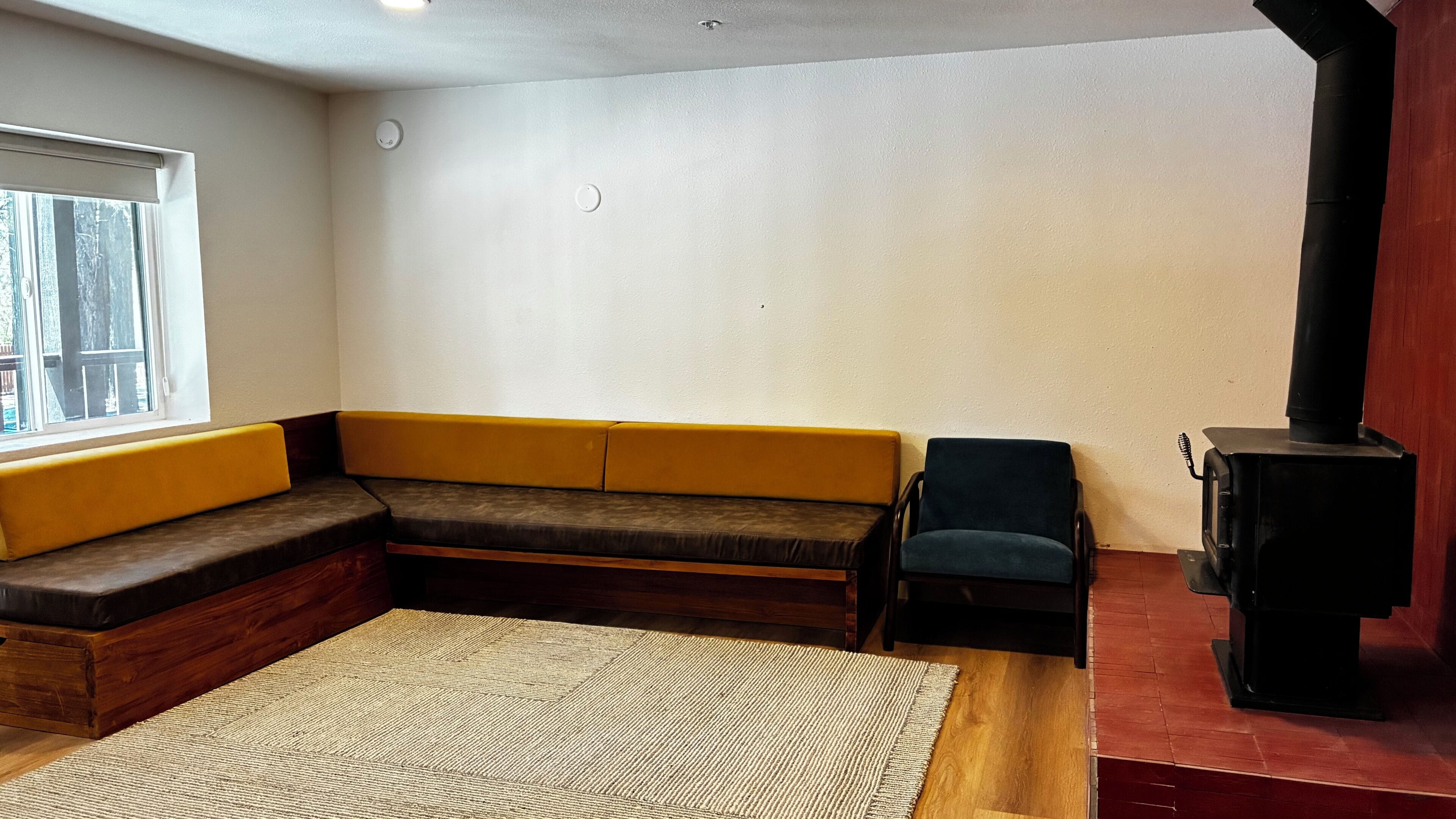 Una sala de estar con un banco de madera, un sofá, una mesita y una chimenea.