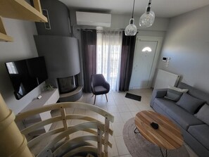 Ein modernes Wohnzimmer mit Flachbildfernseher, Kamin, Sofa, Couchtisch und Sessel.