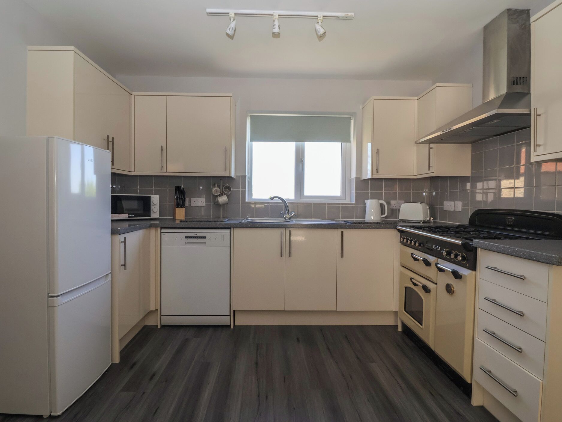 A modern kitchen with a dishwasher, microwave, stove, and sink.