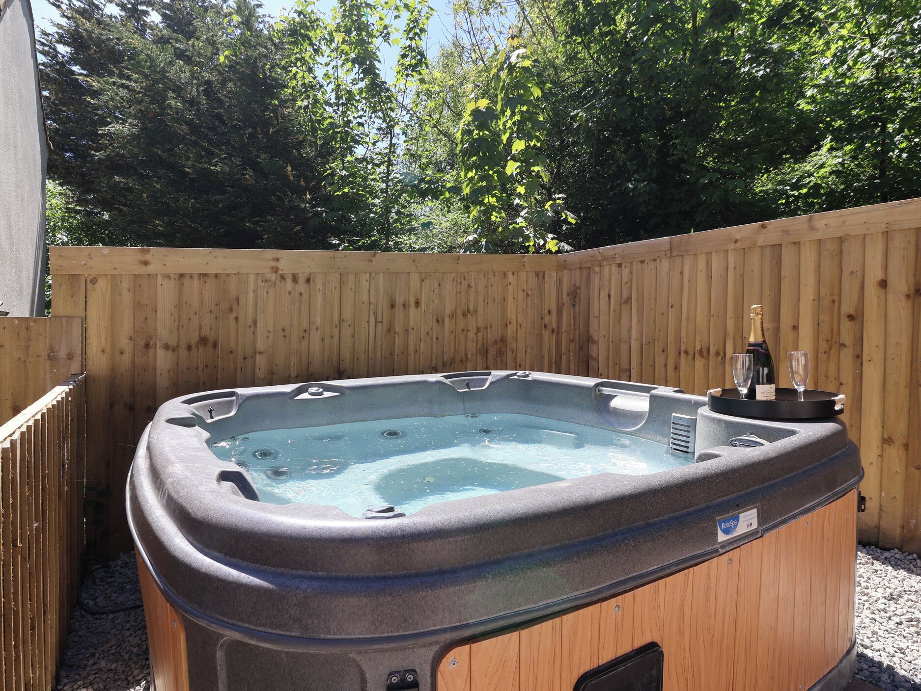 Un jacuzzi con cerca de madera y árboles al fondo.