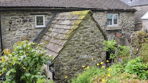 A stone house with a sloped roof, a chimney, and a small window. - Bargate Cottage (Hope Valley)