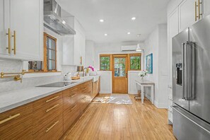 A modern kitchen with wooden cabinets, a stainless steel refrigerator, and a window with a view of greenery. - Spanish Beauty in upscale Coconut Grove, Miami! Best location on Elegant St. (Miami)